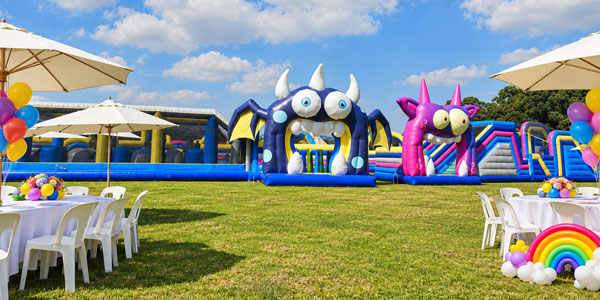 The Gauntlet inflatable obstacle course on a lawn, framed by party tables, white parasols and colourful balloon decorations